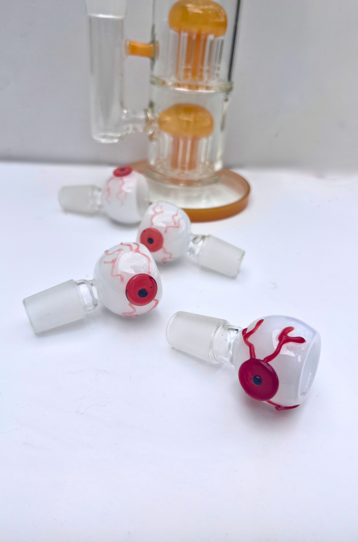 Glass smoking accessories with eye design on a white surface